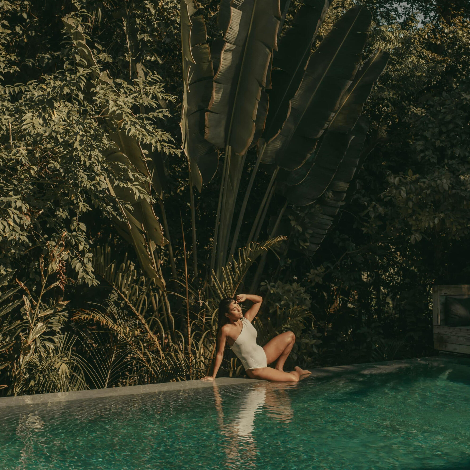 Inside Wellness Travel Design Luxury Tailor made Wellness Travel Woman in bathing suit relaxing at tropical pool