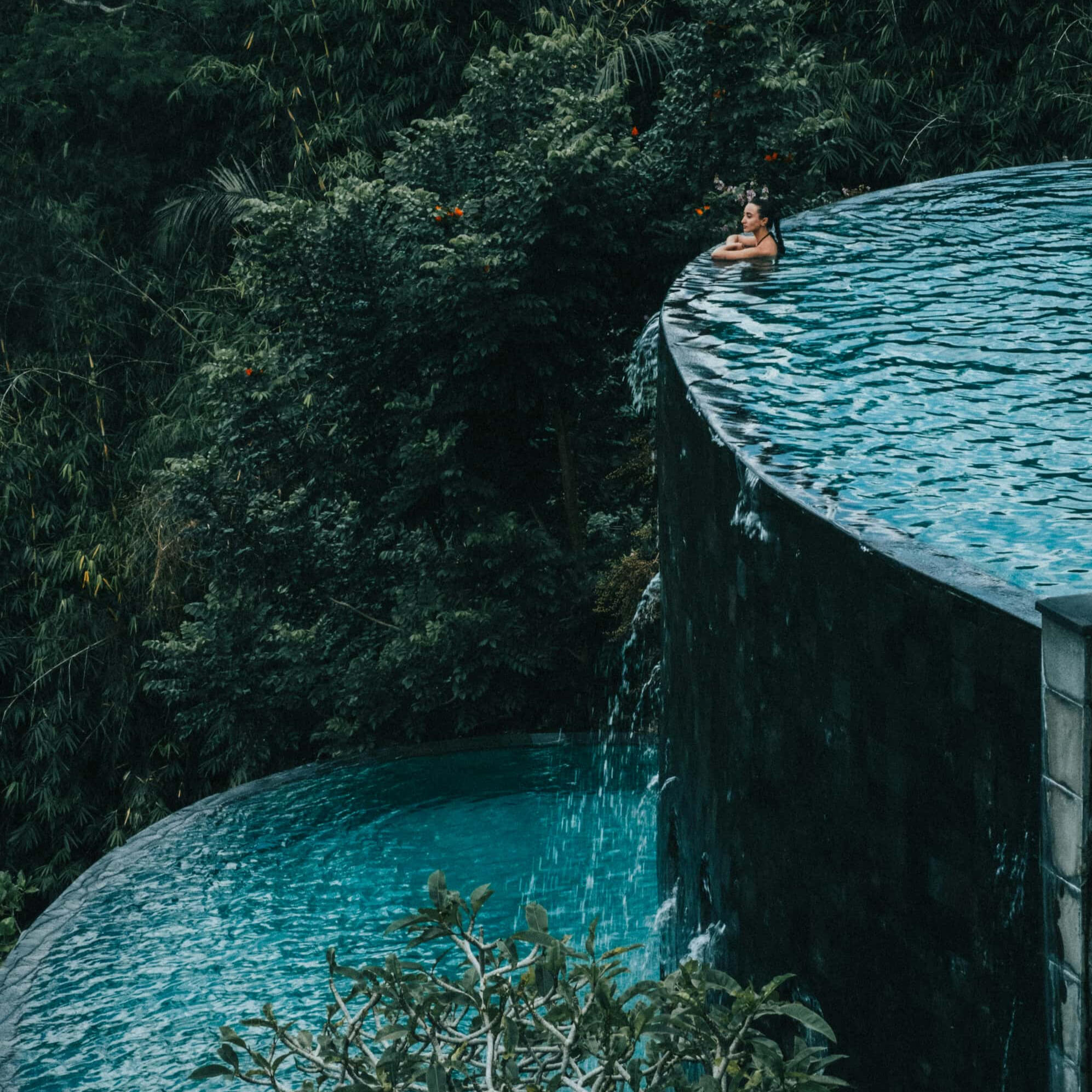 Inside Wellness Travel Create your own retreat Woman at the edge of a two level pool surrounded by nature